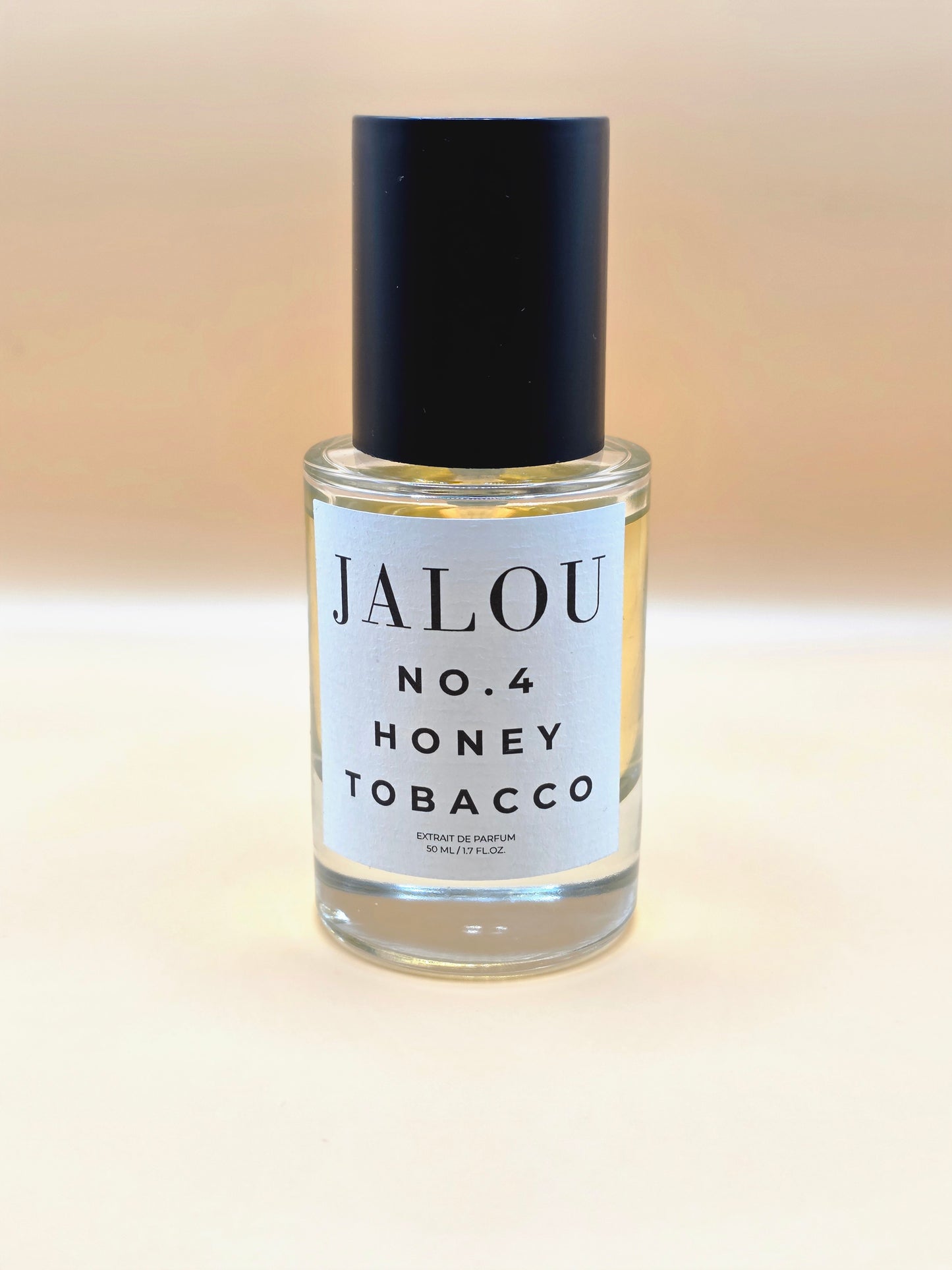 Ein 50ml Flakon JALOU NO. 4 HONEY TOBACCO Extrait de Parfum vor einem hellen, beigefarbenen Hintergrund.