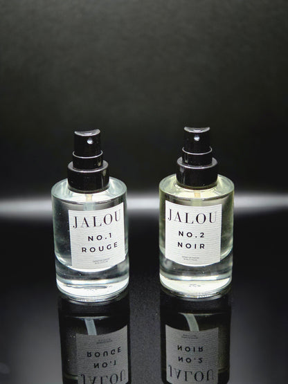 Zwei JALOU Extrait de Parfum Flakons – NO. 1 ROUGE und NO. 2 NOIR – nebeneinander auf einer schwarzen, spiegelnden Oberfläche.