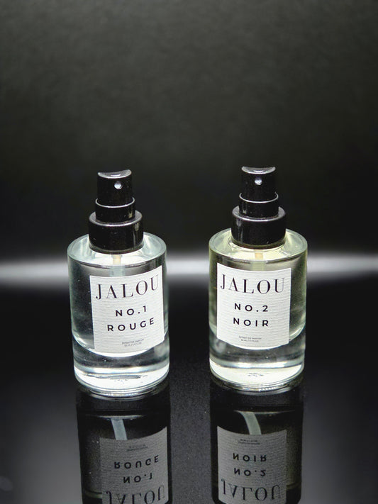 Zwei JALOU Extrait de Parfum Flakons – NO. 1 ROUGE und NO. 2 NOIR – nebeneinander auf einer schwarzen, spiegelnden Oberfläche.