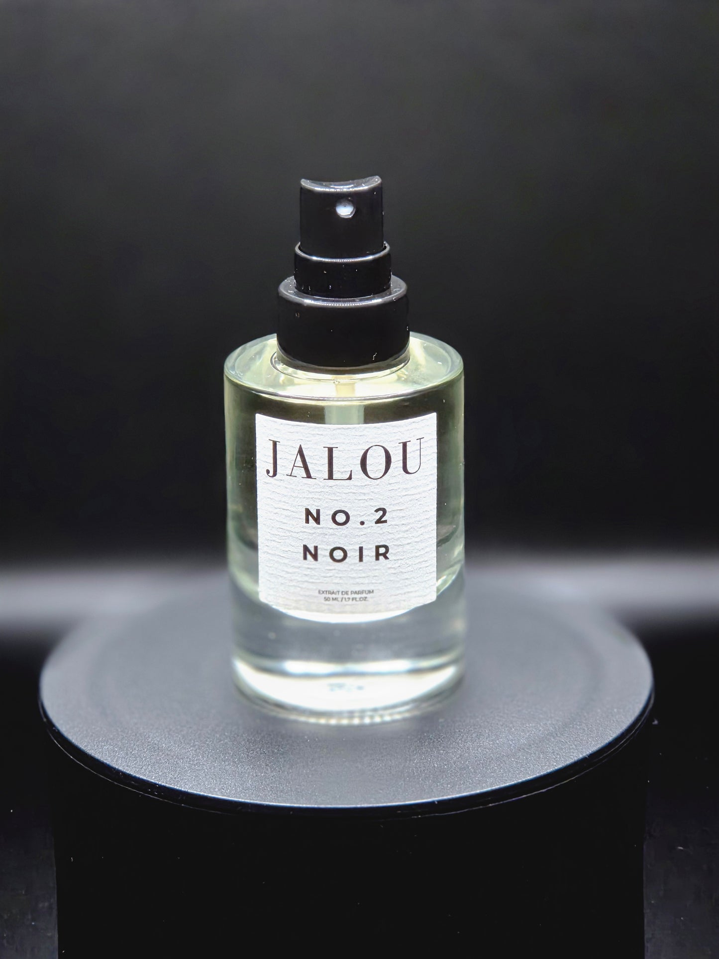 JALOU NO. 2 NOIR Extrait de Parfum – Detailansicht des Flakons auf schwarzem Podest vor dunklem Hintergrund.