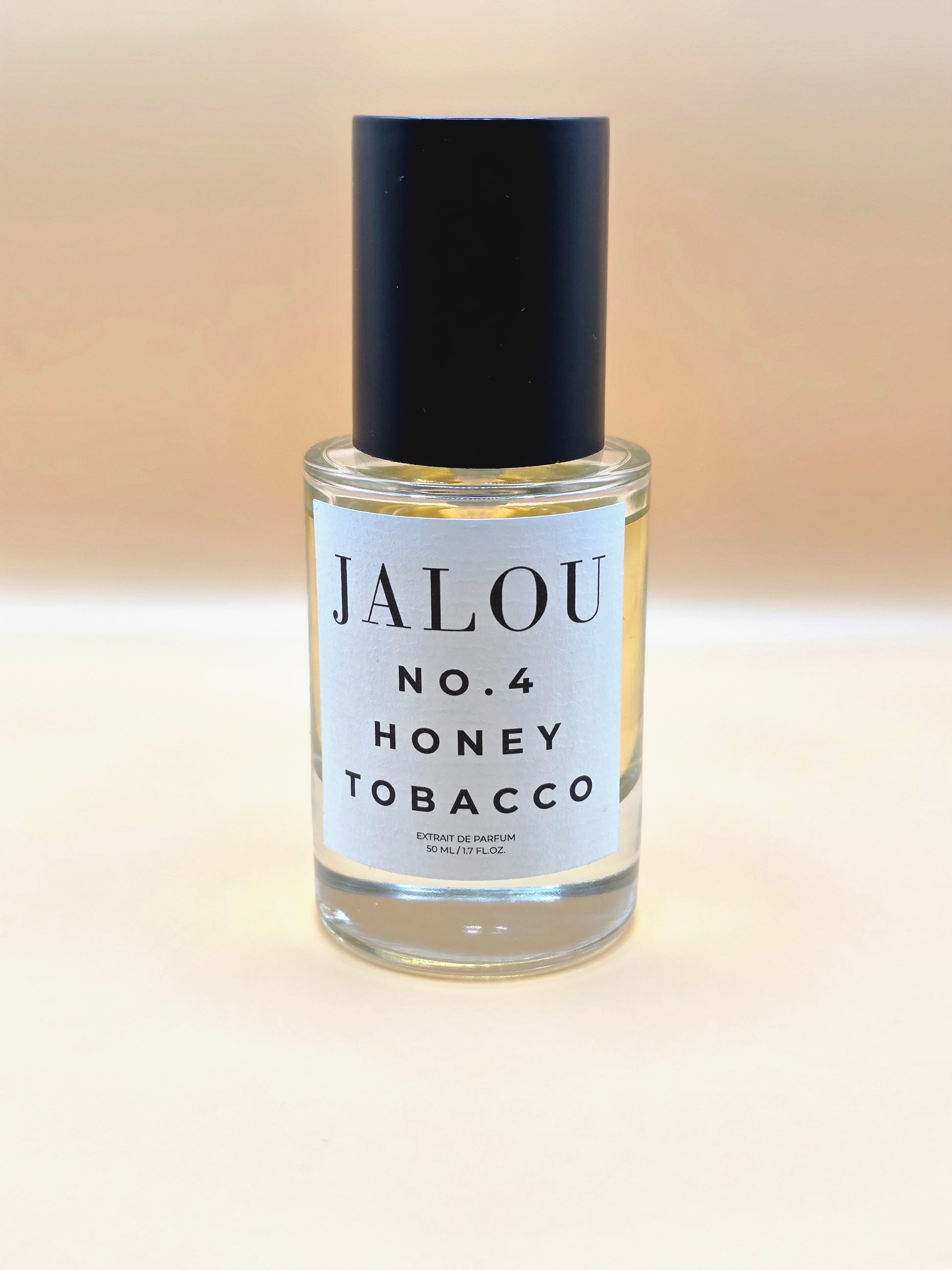 Ein 50ml Flakon JALOU NO. 4 HONEY TOBACCO Extrait de Parfum vor einem hellen, beigefarbenen Hintergrund.