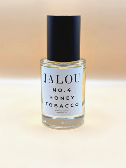 Ein 50ml Flakon JALOU NO. 4 HONEY TOBACCO Extrait de Parfum vor einem hellen, beigefarbenen Hintergrund.