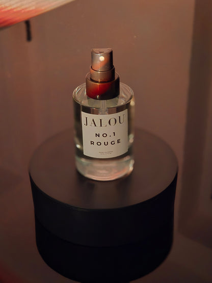 JALOU NO.1 ROUGE Extrait de Parfum 50ml Flakon auf einem schwarzen Sockel mit mystischen roten und goldenen Rauchschwaden im Hintergrund.